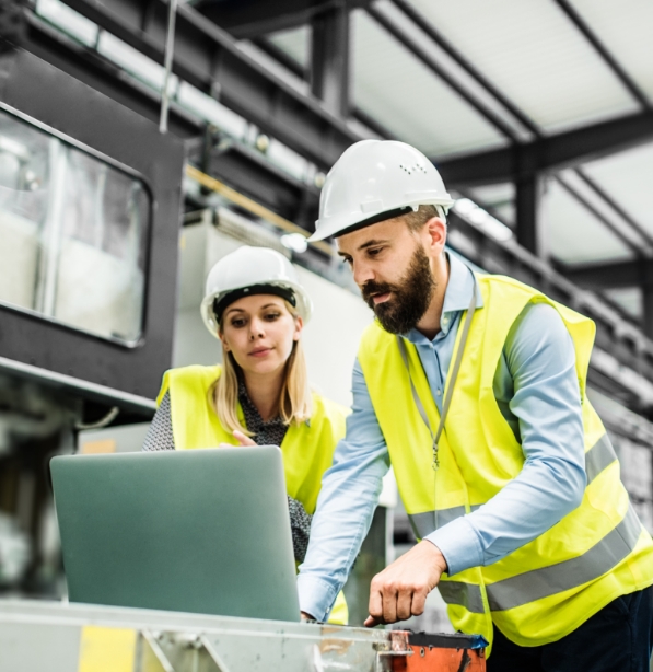 employees in yellow safety vests working together in front of a laptop