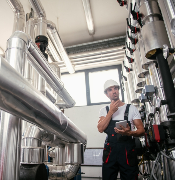 industrial worker holding tablet and standing next to machinery