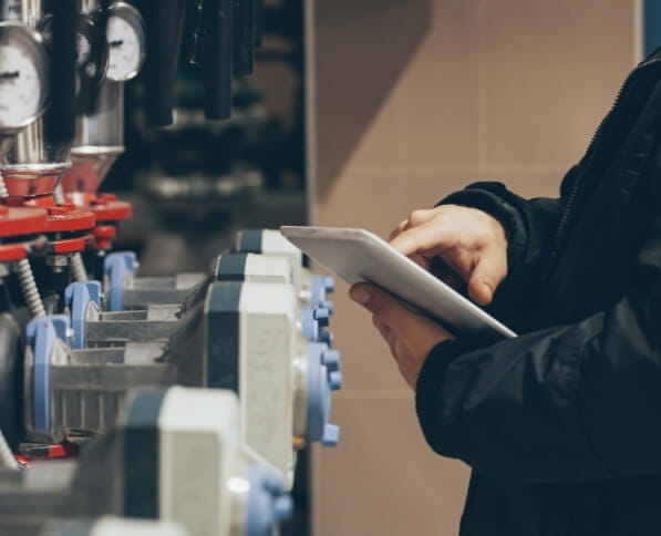 worker calibrates industrial fluid machinery with tablet